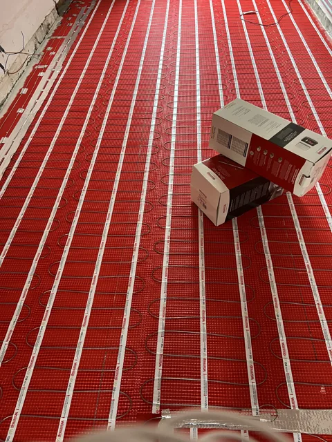 Trame rouge de chauffage électrique au sol en cours de pose